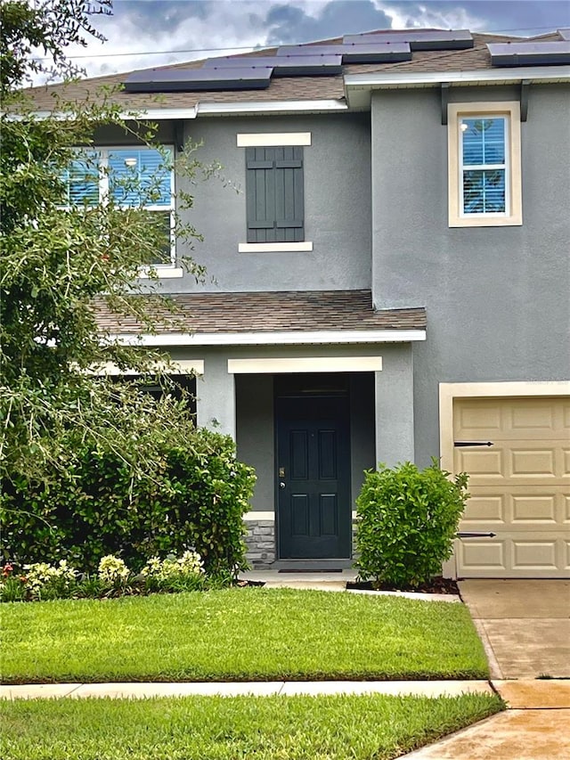 view of front of property featuring a garage, a front lawn, and solar panels