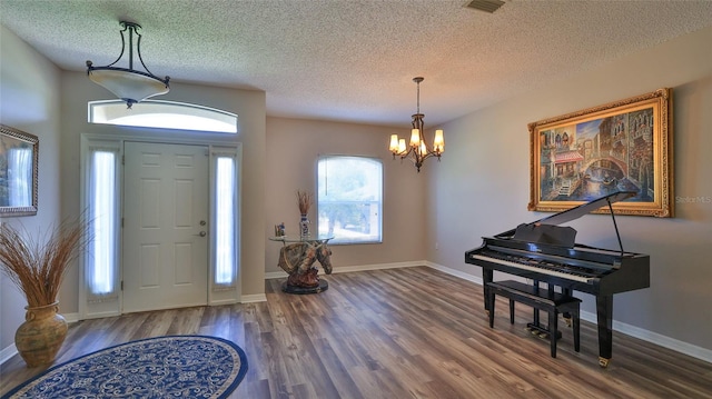 foyer entrance featuring a textured ceiling, hardwood / wood-style floors, and a chandelier