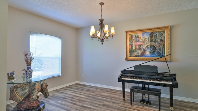 misc room with a healthy amount of sunlight, a textured ceiling, an inviting chandelier, and hardwood / wood-style floors