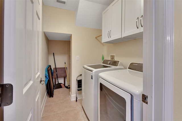 laundry room featuring washing machine and dryer, cabinets, and light tile patterned floors