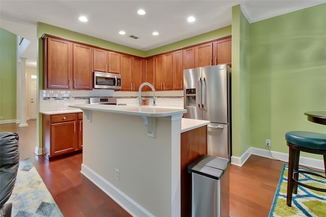 kitchen with appliances with stainless steel finishes, tasteful backsplash, an island with sink, and dark wood-type flooring