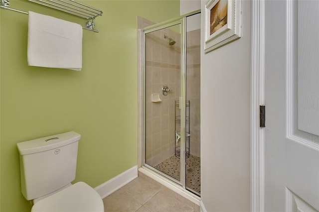 bathroom with tile patterned flooring, a shower with shower door, and toilet