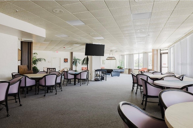 carpeted dining room with a paneled ceiling