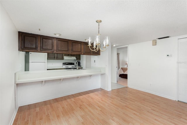 kitchen with a kitchen breakfast bar, pendant lighting, white appliances, and kitchen peninsula