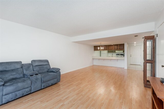 living room featuring a notable chandelier, a textured ceiling, sink, and light hardwood / wood-style floors