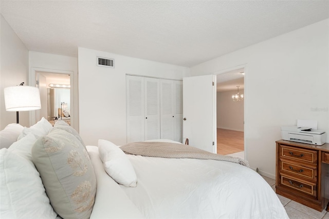 bedroom with connected bathroom, light tile patterned floors, a textured ceiling, and a closet