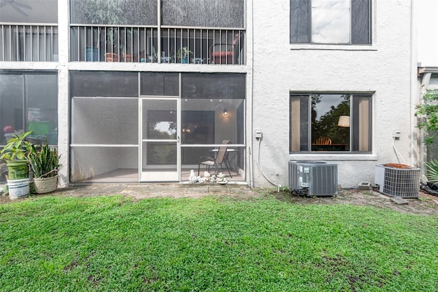 back of house featuring a sunroom, cooling unit, and a lawn