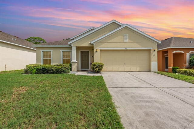 ranch-style home with a garage and a yard