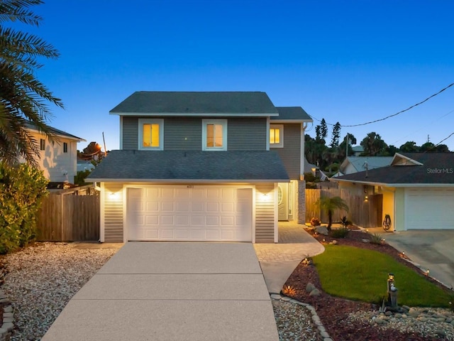 traditional-style house featuring concrete driveway, an attached garage, and fence