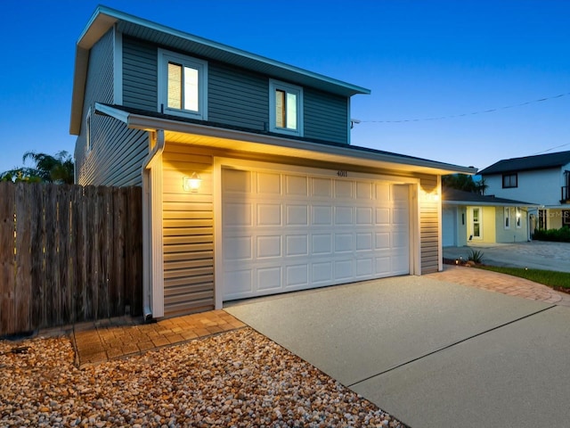 view of front facade featuring a garage, driveway, and fence