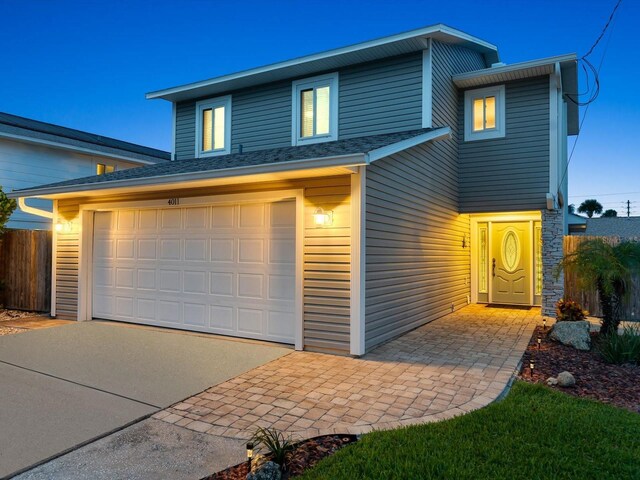 traditional-style house with an attached garage, fence, and concrete driveway