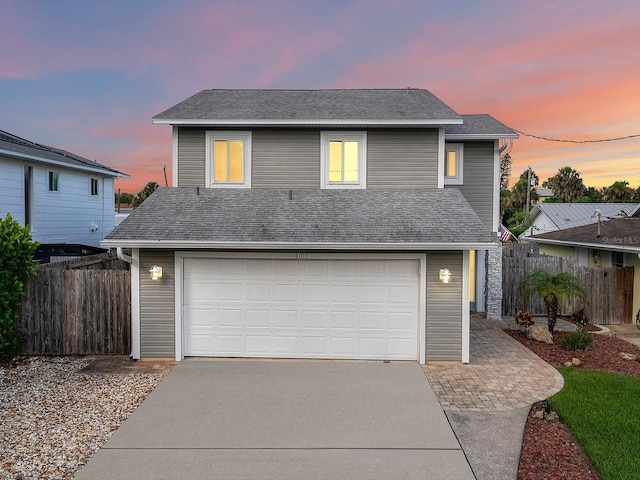 traditional-style home with a garage, fence, concrete driveway, and roof with shingles