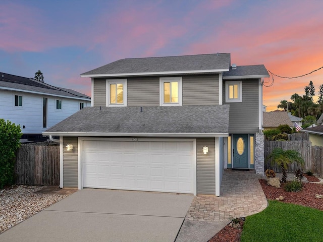 traditional-style home featuring an attached garage, fence, and concrete driveway