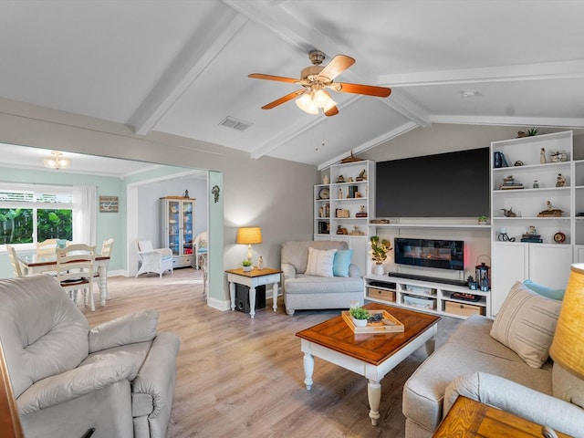 living room with lofted ceiling with beams, ceiling fan, light wood-style flooring, visible vents, and a glass covered fireplace