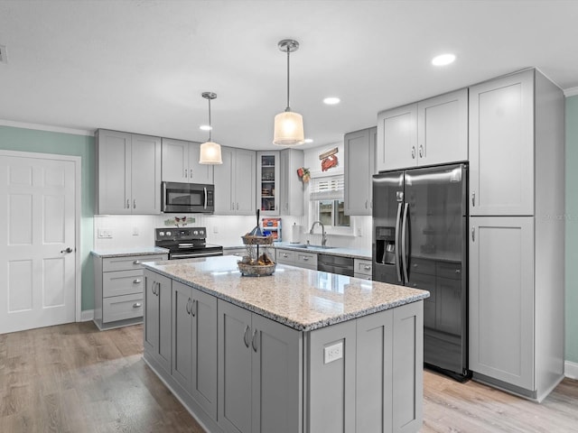 kitchen featuring light stone counters, stainless steel appliances, gray cabinets, light wood-style flooring, and a sink