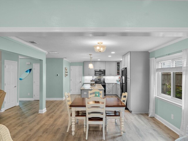 dining area featuring ornamental molding, light wood-style flooring, visible vents, and baseboards