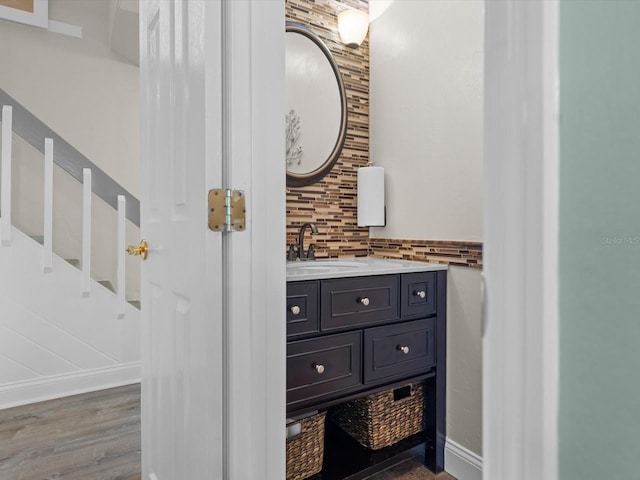 bathroom featuring tasteful backsplash, wood finished floors, vanity, and baseboards