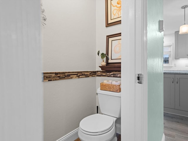 bathroom featuring baseboards, vanity, toilet, and wood finished floors