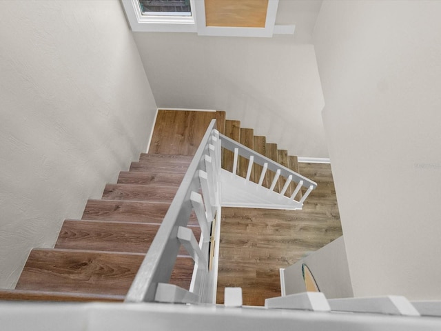 stairway featuring a textured wall and wood finished floors