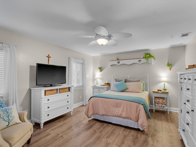 bedroom with light wood finished floors, visible vents, baseboards, and a ceiling fan