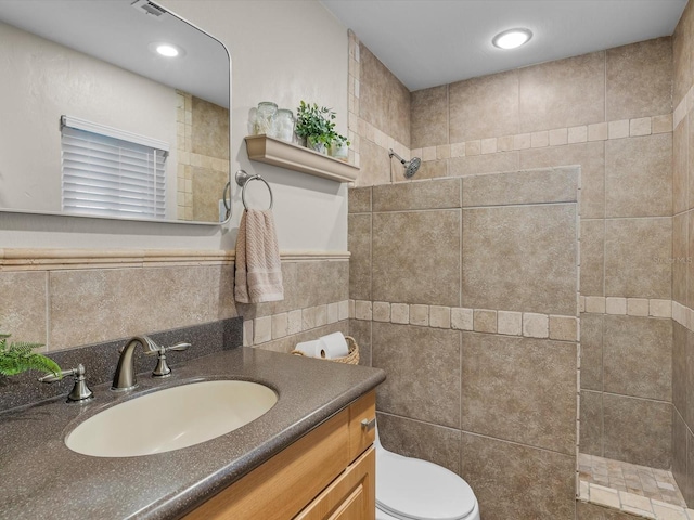 full bathroom with wainscoting, toilet, walk in shower, vanity, and tile walls