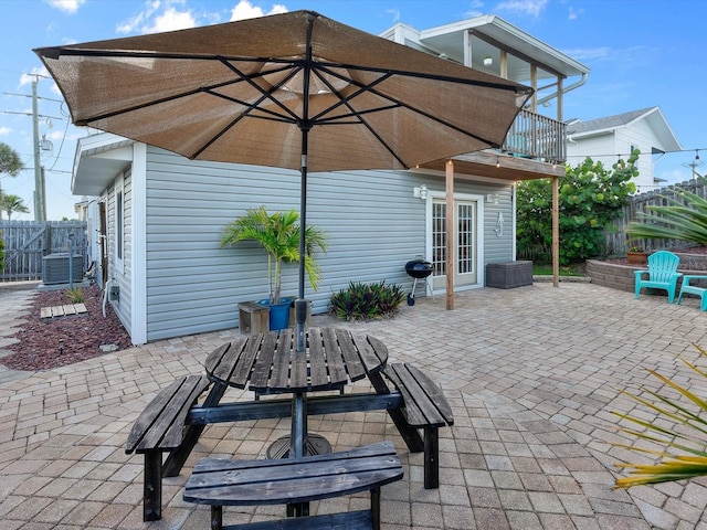 view of patio / terrace featuring french doors, outdoor dining space, fence, and a balcony