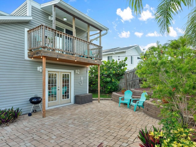 view of patio / terrace featuring french doors, fence, and a balcony