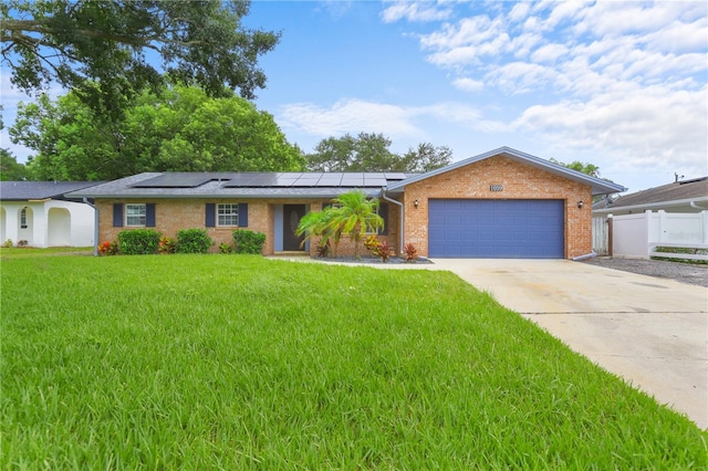 ranch-style home with a front lawn, solar panels, and a garage