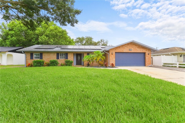 ranch-style home with a front yard, solar panels, and a garage