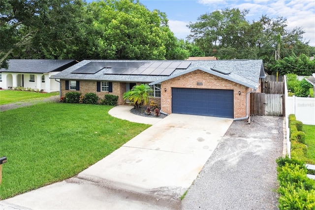 ranch-style home featuring a garage, a front lawn, and solar panels