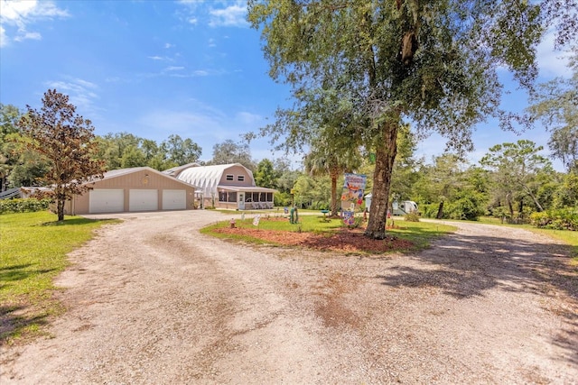 view of front of home with driveway, a front yard, a garage, and an outdoor structure