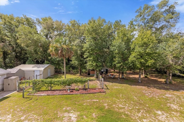 view of yard featuring a garden, fence, a storage unit, and an outbuilding