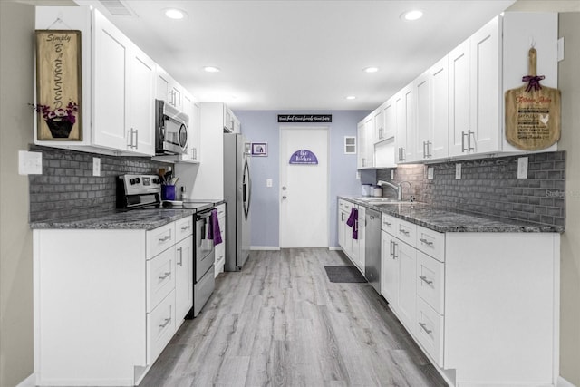 kitchen featuring appliances with stainless steel finishes, light hardwood / wood-style flooring, white cabinets, and decorative backsplash