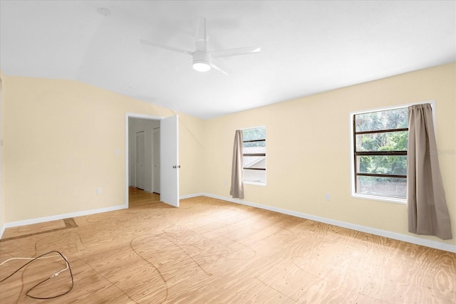 empty room with a wealth of natural light, vaulted ceiling, ceiling fan, and baseboards