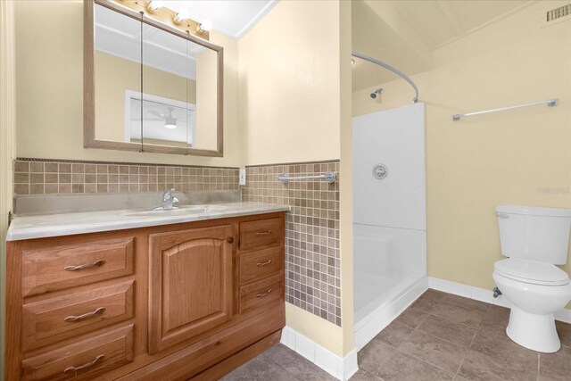 bathroom featuring tile patterned floors, tile walls, vanity, and toilet