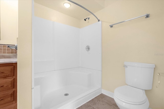 bathroom with baseboards, toilet, tile patterned flooring, walk in shower, and vanity