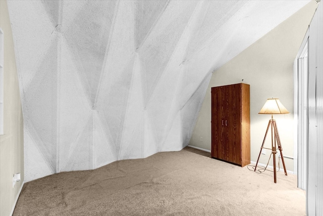 bonus room with a textured ceiling, lofted ceiling, and light colored carpet