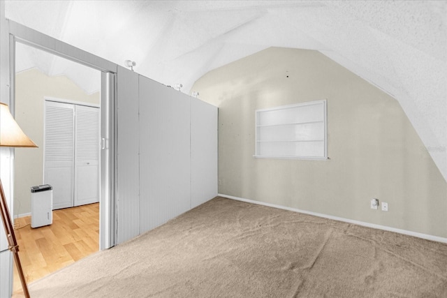 bonus room featuring a textured ceiling, vaulted ceiling, built in shelves, and light hardwood / wood-style floors