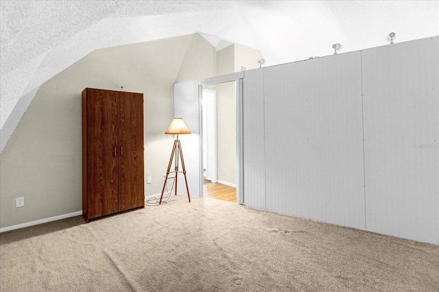 bonus room with a textured ceiling, vaulted ceiling, and light colored carpet