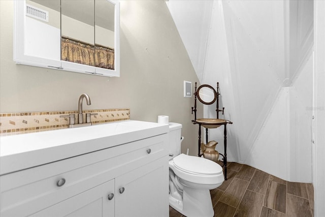 bathroom with wood-type flooring, vanity, and toilet