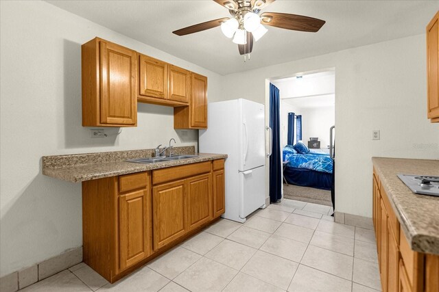 kitchen with light tile patterned floors, sink, ceiling fan, and white fridge