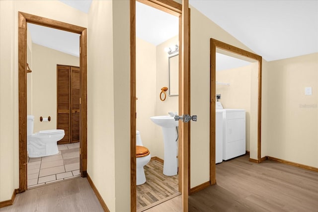 corridor with washer / dryer, sink, vaulted ceiling, and light hardwood / wood-style floors