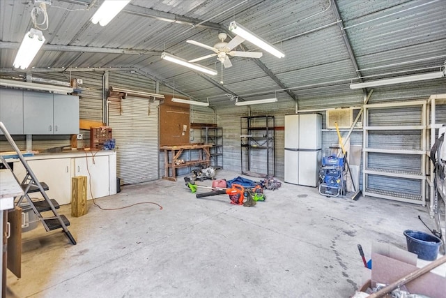 garage featuring ceiling fan, a workshop area, metal wall, and freestanding refrigerator