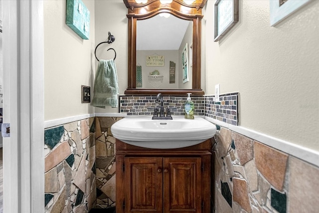 bathroom featuring a wainscoted wall, vanity, and tile walls