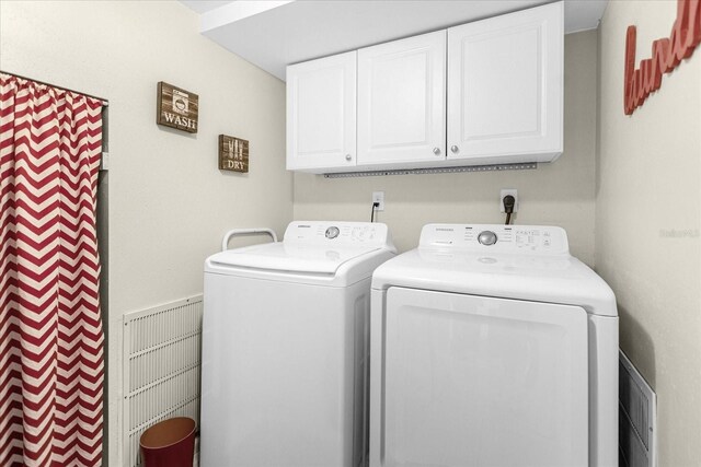 laundry room featuring washing machine and clothes dryer and cabinets