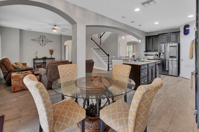 dining area with light wood-type flooring, sink, and ceiling fan