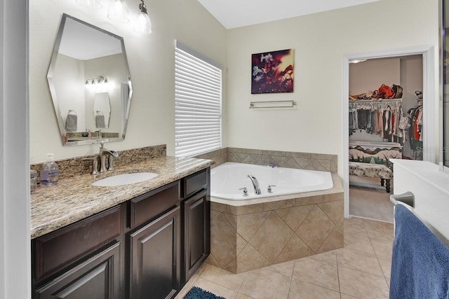 bathroom featuring tiled tub, vanity, and tile patterned flooring