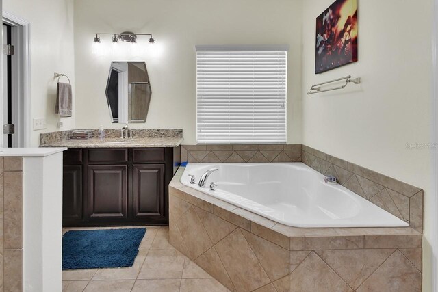 bathroom featuring a relaxing tiled tub, vanity, and tile patterned flooring