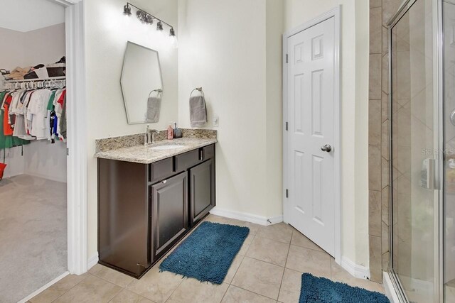 bathroom with tile patterned floors, walk in shower, and vanity