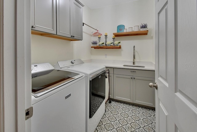 laundry area featuring light tile patterned floors, washer and clothes dryer, cabinets, and sink